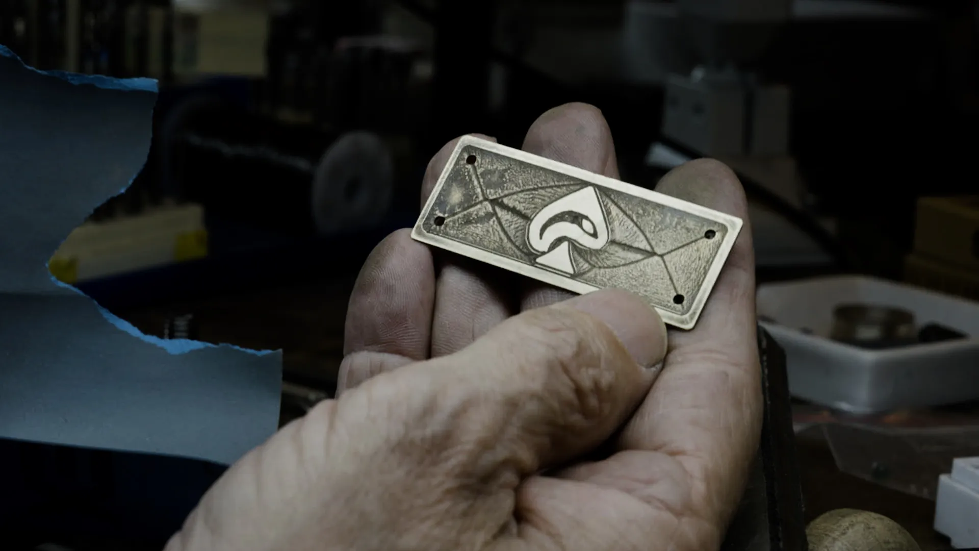 The goldsmith's hand holding the finished Iron Pike brass badge