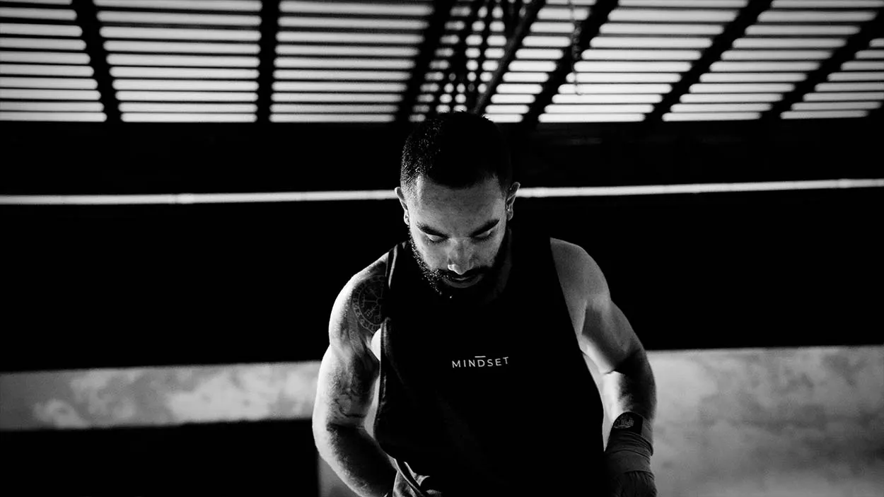 Boxer Thales pulling on the Mindset Studio tank top before his match