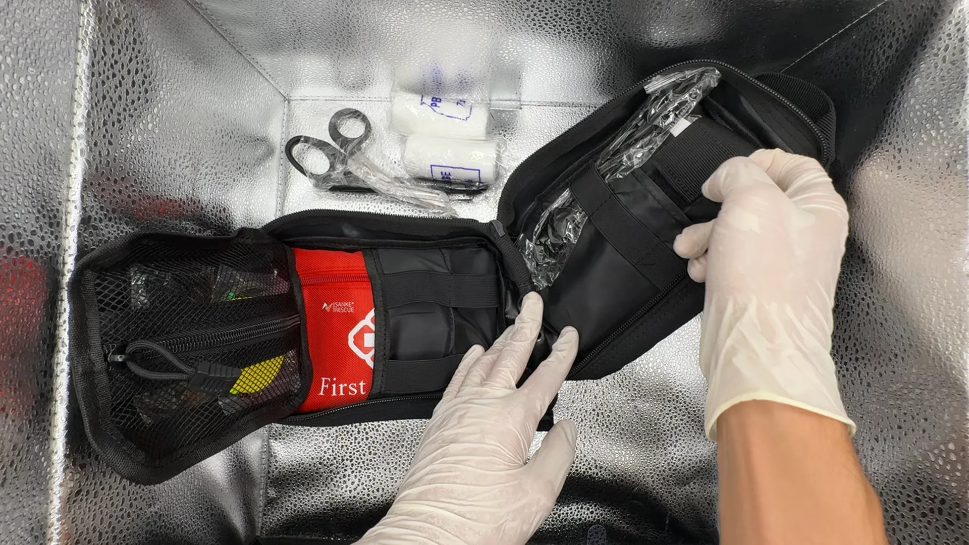 Real in-use photo: gloved hands with an opened Protivex trauma kit