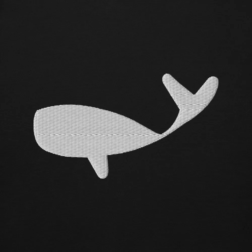 Close-up of the white whale embroidery on black sweat fabric, individual stitches visible